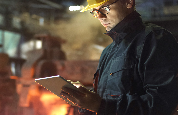 Mann mit Helm und Brille arbeitet am Tablet