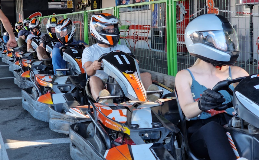 MitarbeiterInnen in Karts mit Helmen