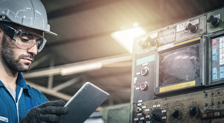 Man with tablet and helmet in front of a production machine