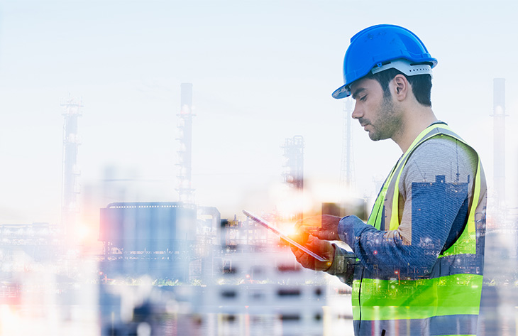 Mann mit Warnweste und Helm arbeitet mit Tablet