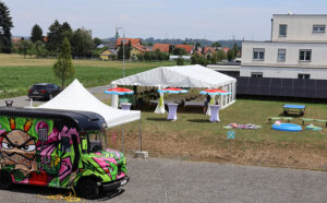 Blick auf das Boom Festzelt, Stehtische, Sonnenschirme, Planschbecken, Picknickdecken und den Börgerer Foodtruck